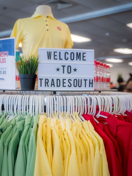 Racks of coloured polo shirts behind a "Welcome to TradeSouth" sign