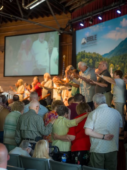 The congregation standing with hands outstretched, praying over people at the front